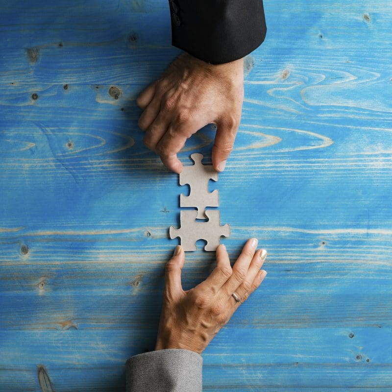 Business partners matching two puzzle pieces in a conceptual image of a merger